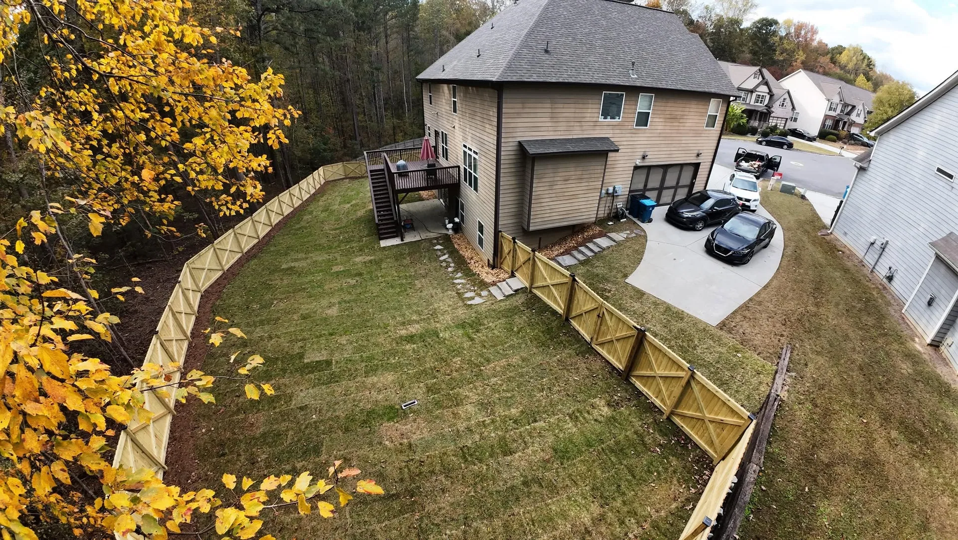 Aerial view wood fence double gate sloped sod backyard deck stairs grayson